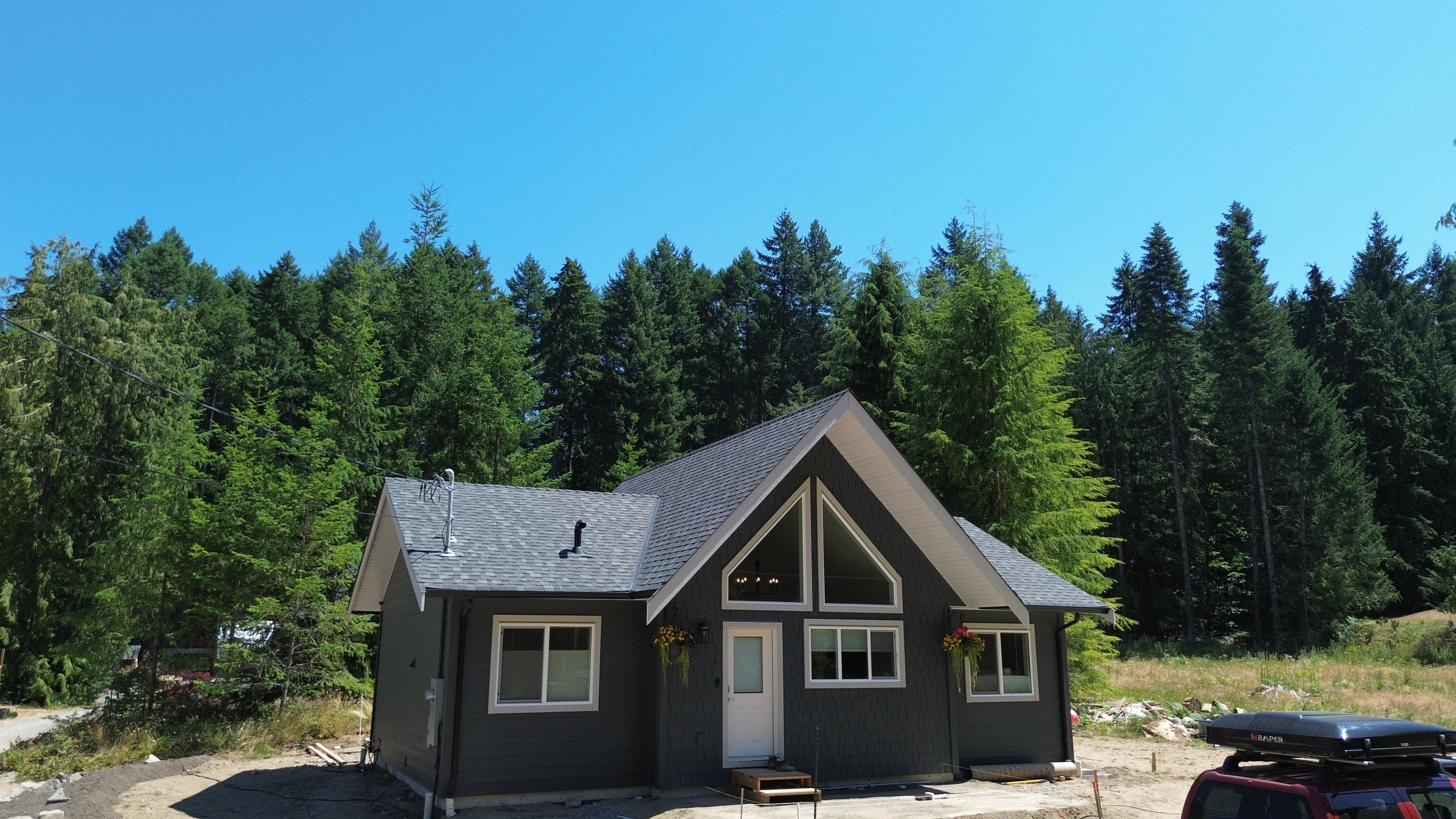 Two-story house with a gray exterior and white trim, surrounded by trees on a clear day.